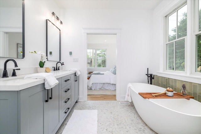 480 Ackerly Pond Ln, Southold, NY 11971 - ensuite bathroom featuring double vanity, a freestanding tub, tasteful backsplash, and speckled floor
