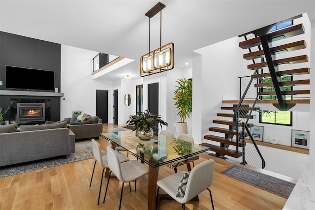 36 Spruce Ln, Poughkeepsie, NY 12603 - dining area with stairway, light wood finished floors, a glass covered fireplace, and a chandelier