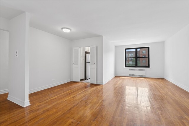 100-11 67th Rd Unit 416, Forest Hills, NY 11375 - spare room with radiator, wood finished floors, and baseboards