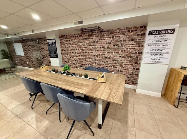 210 Pelham Rd Unit 6H, New Rochelle, NY 10805 - dining room with brick wall, a paneled ceiling, light tile patterned floors, and baseboards