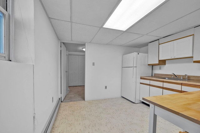 232 County Route 49, Slate Hill, NY 10973 - kitchen with freestanding refrigerator, a sink, a baseboard heating unit, white cabinetry, and a paneled ceiling