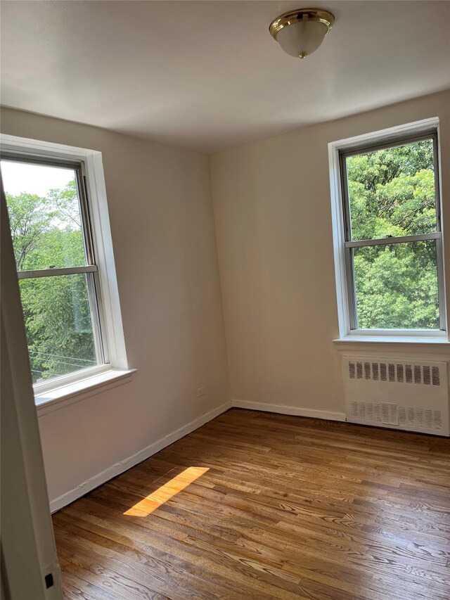4320 E Van Cortlandt Park E Unit 5E, Bronx, NY 10470 - empty room featuring radiator heating unit, plenty of natural light, and wood finished floors