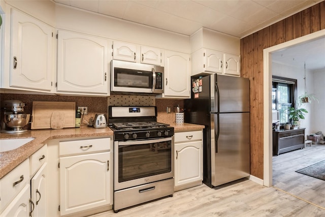 25 Cliffside Dr, Yonkers, NY 10710 - kitchen with stainless steel appliances, decorative backsplash, light wood finished floors, wooden walls, and white cabinetry