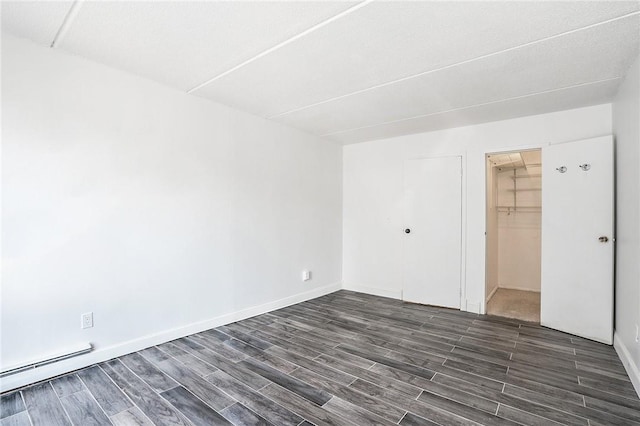 397 N Broadway Unit 3E, Yonkers, NY 10701 - unfurnished bedroom featuring dark wood-type flooring, a closet, a baseboard heating unit, and baseboards