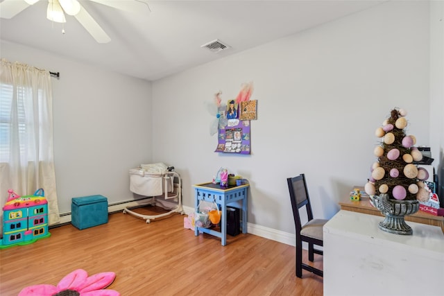 26 Wilson St, Port Jefferson Station, NY 11776 - playroom featuring wood finished floors, a ceiling fan, baseboard heating, and baseboards