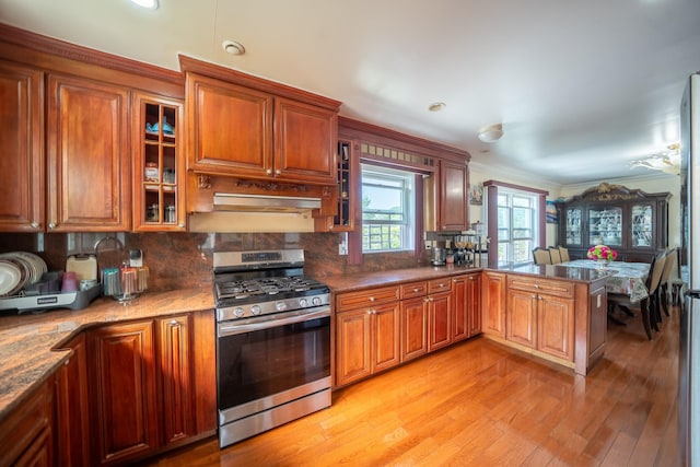 580 Valley Ave, Yonkers, NY 10703 - kitchen with stainless steel gas range, crown molding, a peninsula, light wood-style floors, and decorative backsplash