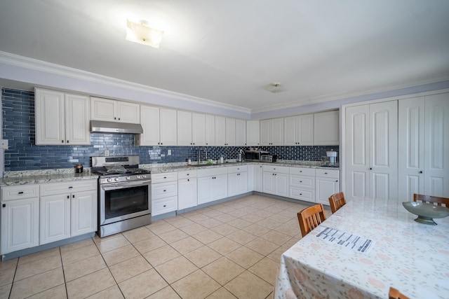 580 Valley Ave, Yonkers, NY 10703 - kitchen with stainless steel gas stove, under cabinet range hood, ornamental molding, light tile patterned floors, and backsplash