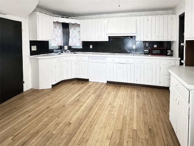 9 Church St, Hyde Park, NY 12538 - kitchen with light wood-style floors, white cabinetry, tasteful backsplash, light countertops, and black appliances