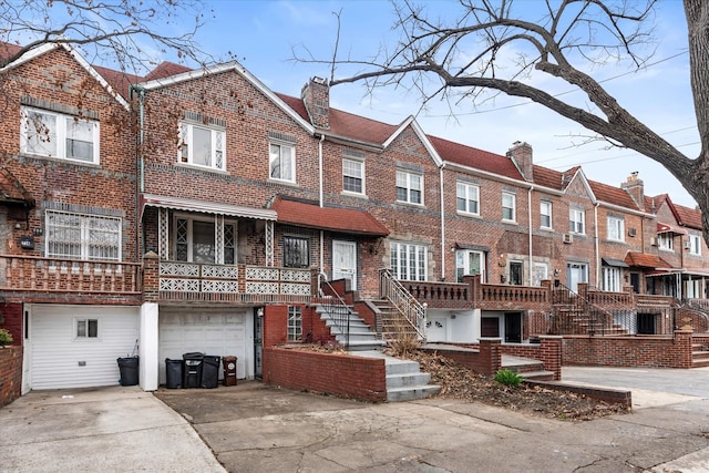 712 E 40th St, Brooklyn, NY 11210 - view of front of property featuring brick siding, a garage, a chimney, concrete driveway, and stairs