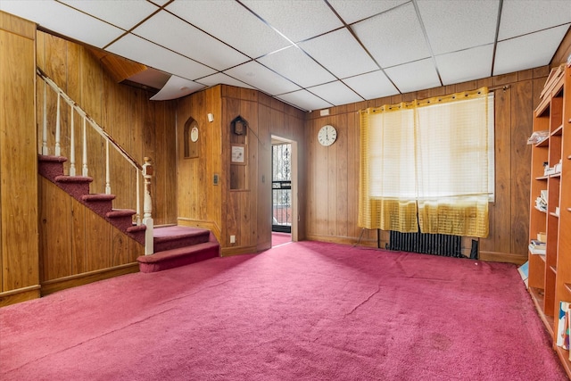 712 E 40th St, Brooklyn, NY 11210 - carpeted living area with wooden walls, stairway, baseboards, and a drop ceiling