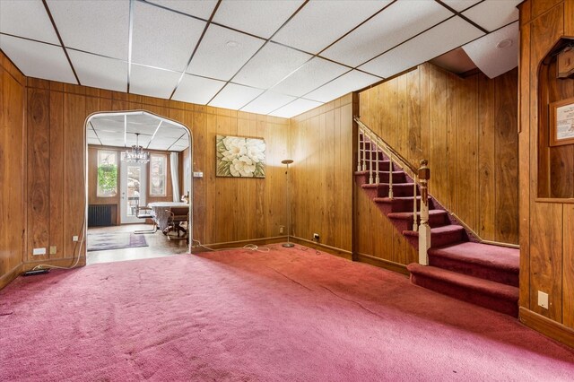712 E 40th St, Brooklyn, NY 11210 - unfurnished living room with wood walls, stairs, a chandelier, carpet flooring, and arched walkways