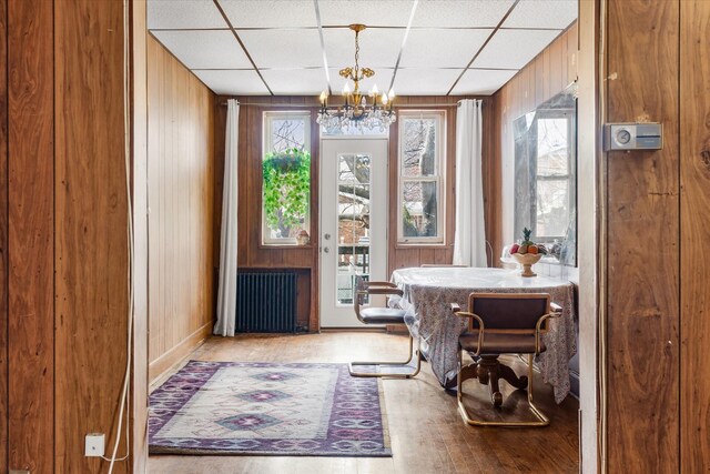 712 E 40th St, Brooklyn, NY 11210 - dining area featuring radiator heating unit, wooden walls, a chandelier, wood finished floors, and a paneled ceiling