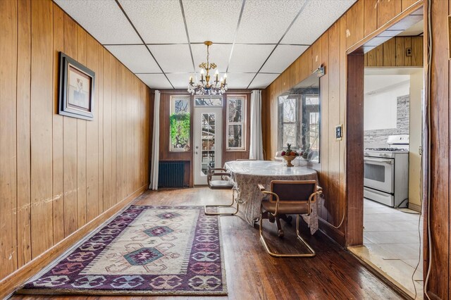 712 E 40th St, Brooklyn, NY 11210 - dining area featuring a chandelier, light wood-style flooring, wood walls, and a drop ceiling