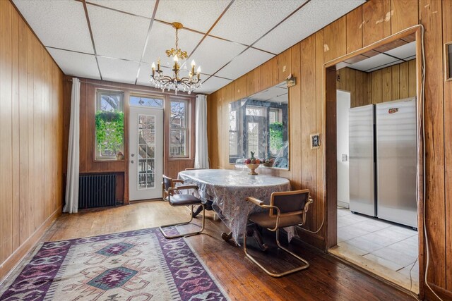 712 E 40th St, Brooklyn, NY 11210 - dining space featuring radiator heating unit, a chandelier, wood walls, healthy amount of natural light, and light wood-style floors