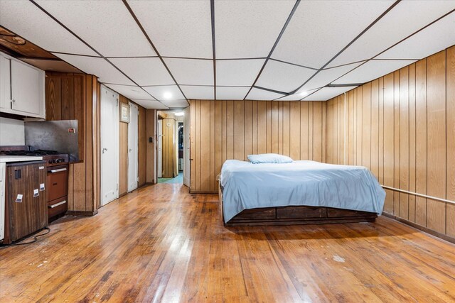 712 E 40th St, Brooklyn, NY 11210 - bedroom featuring light wood-style floors, a drop ceiling, and wood walls