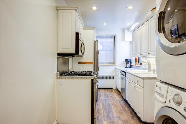 2 Town House Pl Unit 2H, Great Neck, NY 11021 - kitchen featuring a sink, stacked washer / drying machine, appliances with stainless steel finishes, light countertops, and white cabinetry