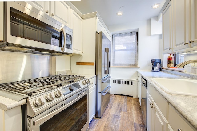 2 Town House Pl Unit 2H, Great Neck, NY 11021 - kitchen featuring stainless steel appliances, a sink, light wood-style flooring, white cabinets, and recessed lighting
