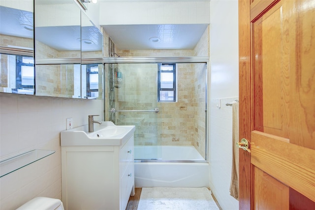 2 Town House Pl Unit 2H, Great Neck, NY 11021 - bathroom featuring tile walls, vanity, bath / shower combo with glass door, and toilet