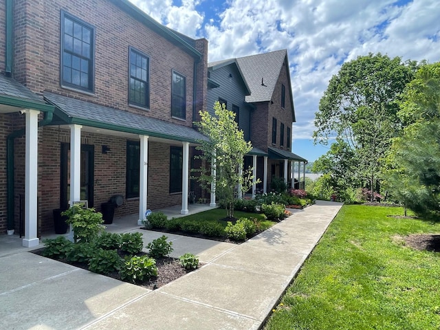 view of home's exterior with brick siding, a lawn, and covered porch