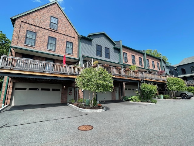 multi unit property with an attached garage, asphalt driveway, and brick siding