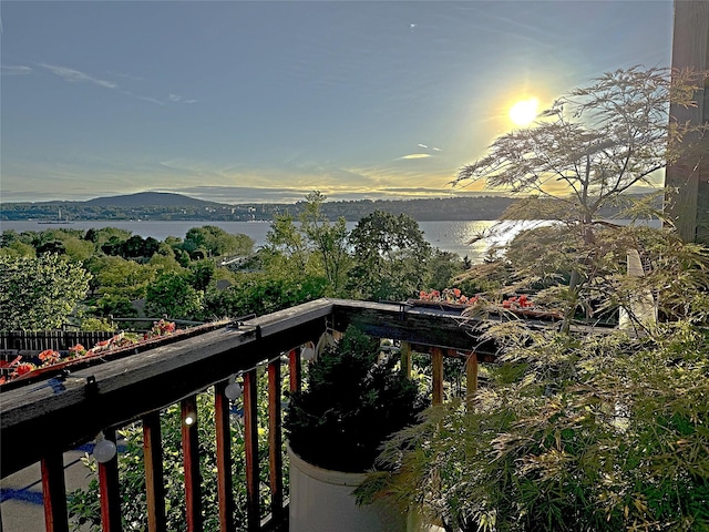 balcony at dusk featuring a water view