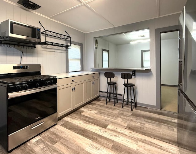 284 Titusville Rd, Poughkeepsie, NY 12603 - kitchen with stainless steel appliances, light wood-type flooring, baseboard heating, a breakfast bar area, and light countertops