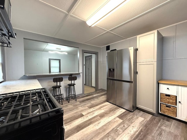 284 Titusville Rd, Poughkeepsie, NY 12603 - kitchen with stainless steel fridge with ice dispenser, black range with gas stovetop, light wood-type flooring, and a breakfast bar