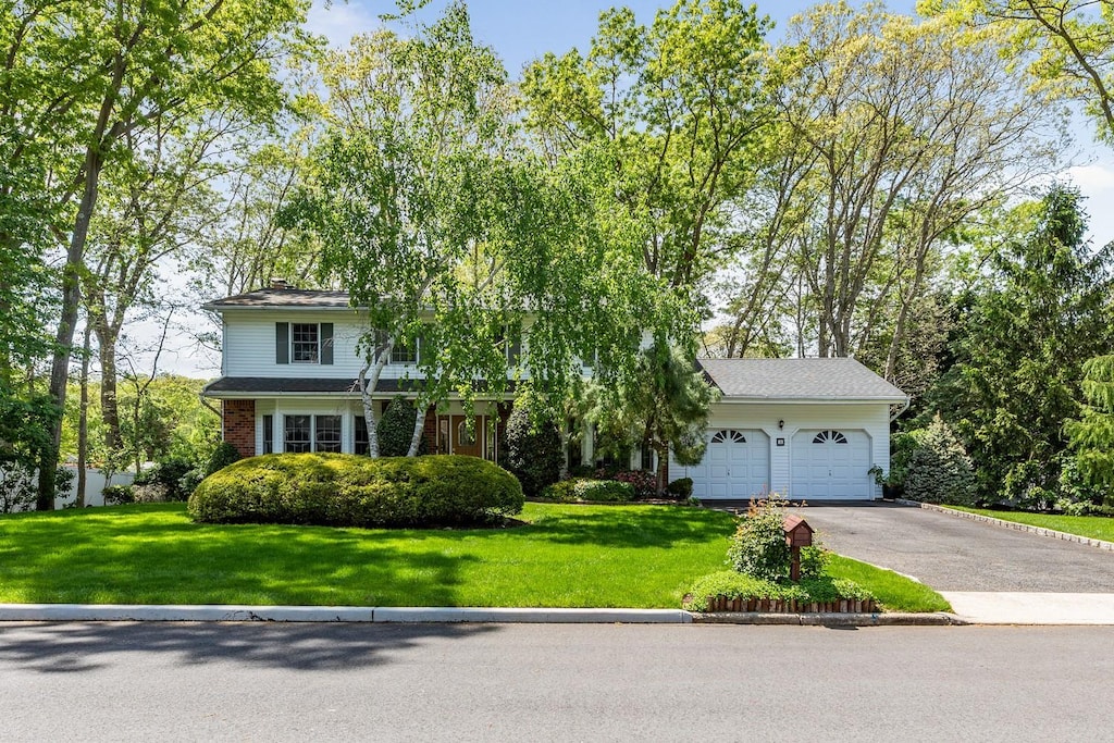 18 Stuyvesant Cir E, East Setauket, NY 11733 - obstructed view of property with driveway, an attached garage, a front yard, and a chimney