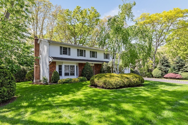 18 Stuyvesant Cir E, East Setauket, NY 11733 - traditional-style house with a chimney, a front yard, and brick siding