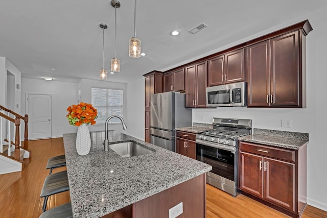37 Lindentree Ln, Middletown, NY 10940 - kitchen with appliances with stainless steel finishes, a sink, a breakfast bar area, light stone countertops, and light wood-style floors