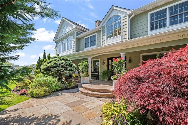 view of exterior entry featuring covered porch and a chimney