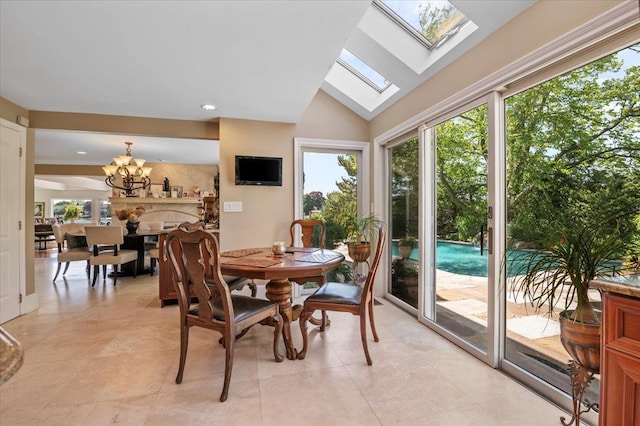 dining space featuring healthy amount of natural light, a chandelier, vaulted ceiling, a skylight, and light tile patterned floors