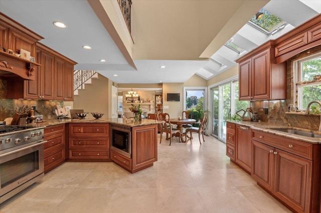 kitchen with appliances with stainless steel finishes, a sink, light stone countertops, brown cabinetry, and tasteful backsplash