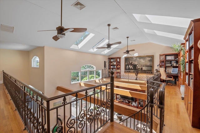 staircase with a skylight, a ceiling fan, lofted ceiling, and wood finished floors
