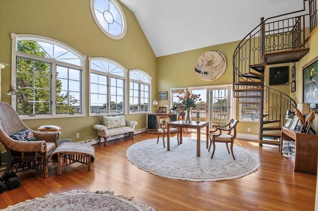 dining area featuring stairs, healthy amount of natural light, high vaulted ceiling, wood finished floors, and baseboard heating