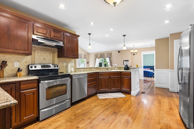 135 Ray Blvd, Poughkeepsie, NY 12603 - kitchen featuring stainless steel appliances, under cabinet range hood, a peninsula, light wood-type flooring, and decorative light fixtures
