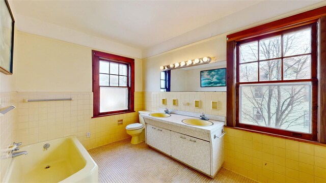 55 Teller Ave, Beacon, NY 12508 - bathroom with tile walls, tile patterned floors, wainscoting, a bath, and toilet