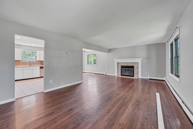 54 Capital Dr, Washingtonville, NY 10992 - unfurnished living room featuring baseboard heating, wood finished floors, and healthy amount of natural light