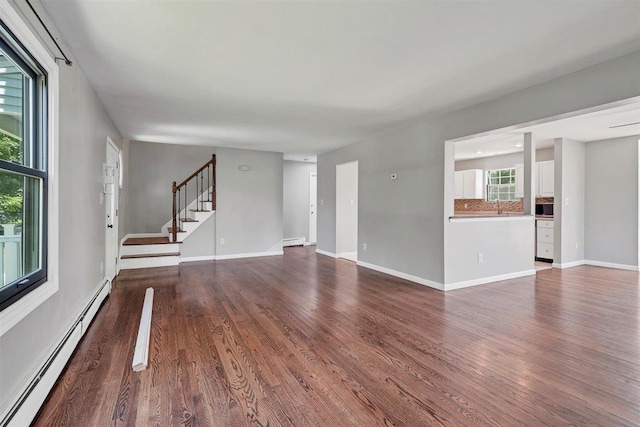 54 Capital Dr, Washingtonville, NY 10992 - unfurnished living room with a baseboard radiator, dark wood-style flooring, stairway, and baseboards