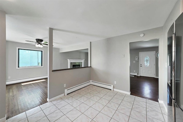 54 Capital Dr, Washingtonville, NY 10992 - empty room featuring baseboard heating, ceiling fan, a fireplace, a baseboard heating unit, and light wood finished floors