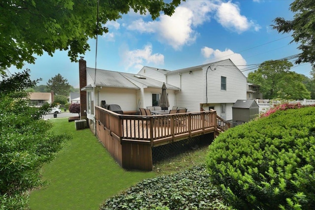 10 Linda Ln, Plainview, NY 11803 - back of property featuring a chimney, a deck, a lawn, and central AC