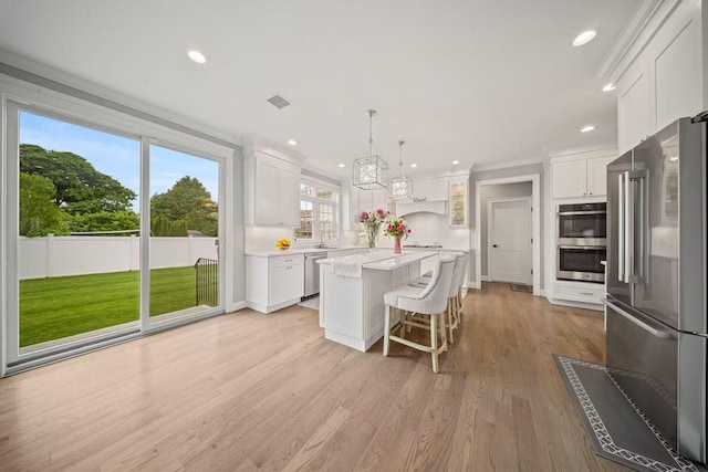 1427 Bellmore Rd, North Bellmore, NY 11710 - kitchen with appliances with stainless steel finishes, a kitchen island, light countertops, white cabinets, and decorative backsplash