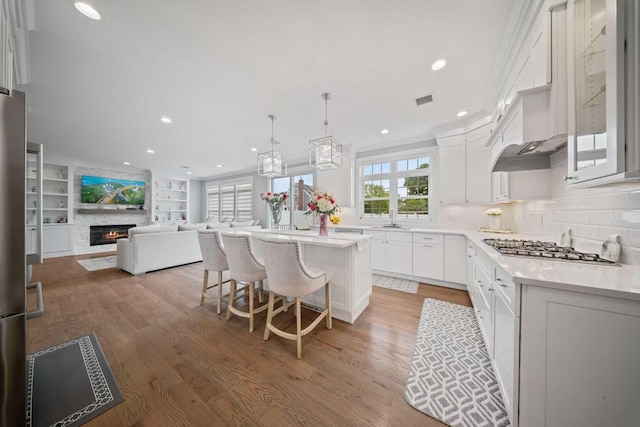 1427 Bellmore Rd, North Bellmore, NY 11710 - kitchen with stainless steel gas stovetop, light wood finished floors, a kitchen island, white cabinets, and recessed lighting