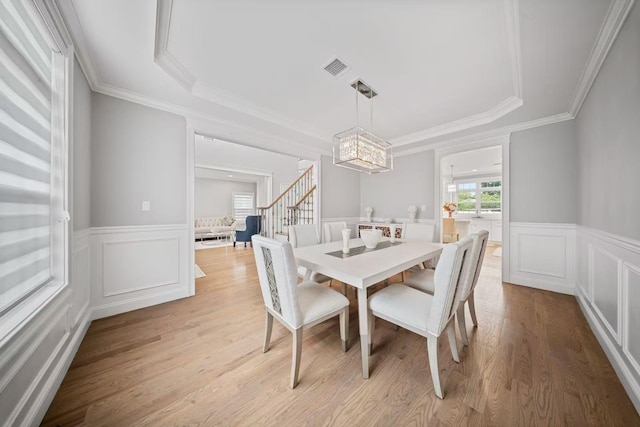 1427 Bellmore Rd, North Bellmore, NY 11710 - dining area featuring a chandelier, wainscoting, light wood finished floors, a decorative wall, and crown molding