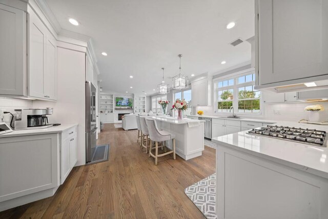 1427 Bellmore Rd, North Bellmore, NY 11710 - kitchen featuring appliances with stainless steel finishes, a sink, wood finished floors, white cabinets, and a breakfast bar area