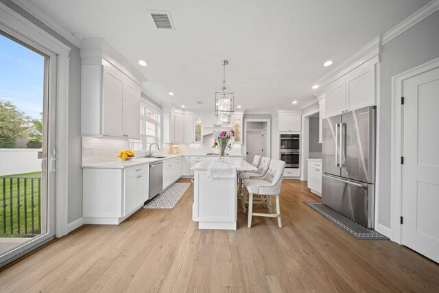 1427 Bellmore Rd, North Bellmore, NY 11710 - kitchen featuring appliances with stainless steel finishes, a sink, a center island, light countertops, and white cabinetry