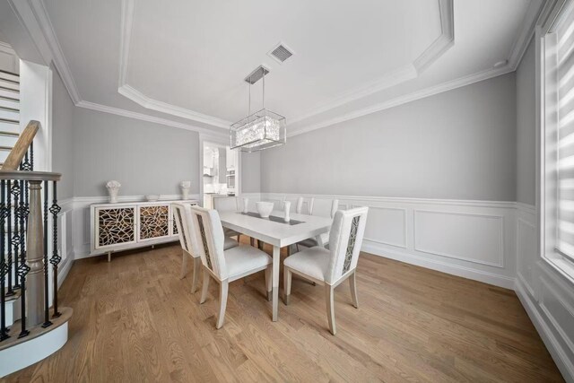 1427 Bellmore Rd, North Bellmore, NY 11710 - dining room with a chandelier, wood finished floors, ornamental molding, a raised ceiling, and a wainscoted wall