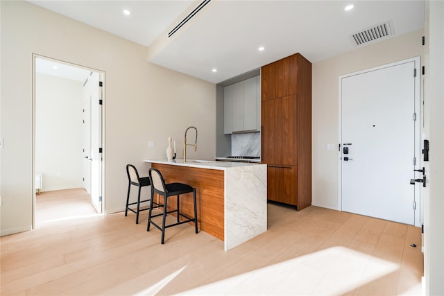 3116 21st St Unit Ph2B, Astoria, NY 11106 - kitchen with a breakfast bar, brown cabinetry, modern cabinets, a peninsula, and light countertops