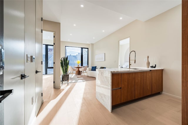 3116 21st St Unit Ph2B, Astoria, NY 11106 - kitchen with modern cabinets, brown cabinetry, a sink, light wood-type flooring, and a peninsula