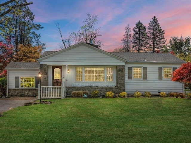 ranch-style house featuring a yard, stone siding, and covered porch